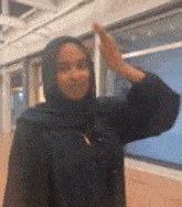 a woman wearing a hijab is waving her hand in the air