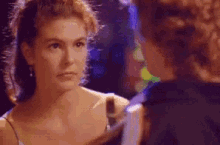 a woman is looking at another woman 's face in a dark room .