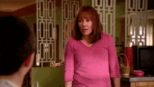 a woman in a pink shirt is standing in front of a man