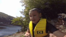 a boy wearing a yellow life jacket with the letter d on the front