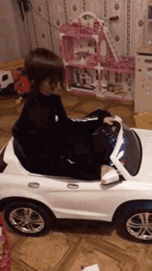 a young girl is sitting in a toy car in a room .
