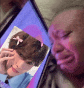 a person is crying while looking at a picture of a boy with a bow in his hair