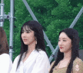 two girls are standing next to each other in front of a green background .
