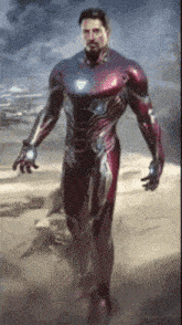 a man in a red suit is standing on a sandy beach .