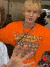 a blurry picture of a person wearing an orange t-shirt that says ' disney ' on it .