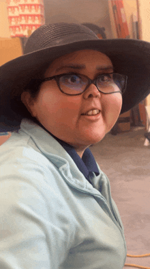 a woman wearing a hat and glasses is smiling for the camera