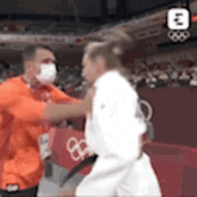 a man wearing a mask is standing next to a man in a white shirt .