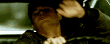 a man is driving a car with his hands on his neck .