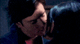 a man and woman are kissing in a bedroom with a picture on the wall