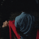 a man in a blue shirt holds a woman in a red dress upside down