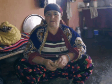 a woman in a colorful floral outfit sits on the floor