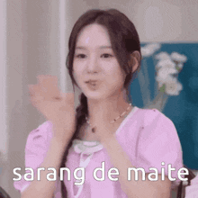 a girl in a pink shirt is clapping her hands and says sarang de maite .