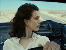 a woman in a white shirt driving a car