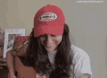 a woman wearing a red hat that says chile is smiling