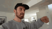 a man with a beard wearing a hat and a grey sweatshirt