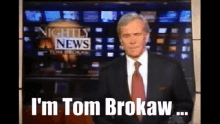 a man in a suit and tie stands in front of a nightly news screen