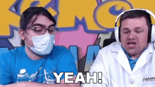 two men wearing face masks and headphones are sitting next to each other and one of them is saying yeah !