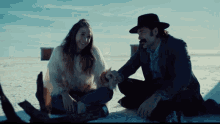 a man and a woman sit on the ground in the snow