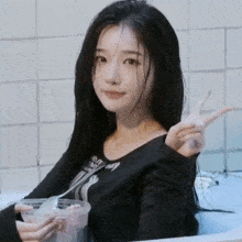 a woman is sitting in a bathtub holding a cup of food and giving the peace sign