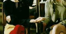 a woman in a green sweater holds the hand of another woman in a black sweater