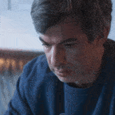 a close up of a man 's face with a blue shirt on