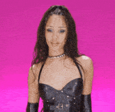 a woman wearing a choker and gloves is standing on a pink background