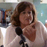 a woman is talking into a microphone and pointing at something