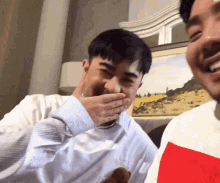a man covering his mouth with his hand while another man looks on