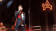a man singing into a microphone in front of a neon sign that says ' ya '