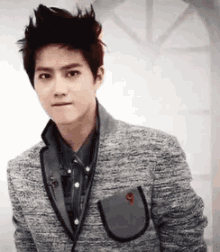 a young man wearing a gray jacket and a denim shirt .