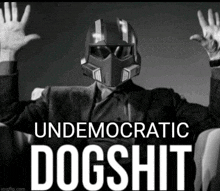 a man in a suit and helmet is sitting in a chair with his hands in the air and the words " undemocratic dogshit " below him