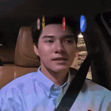 a man wearing a blue shirt and tie is sitting in a car with a seat belt on .