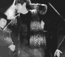 a black and white photo of a man smoking a cigarette on stage .