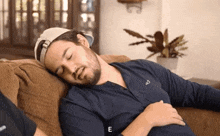 a man with a beard is sleeping on a couch with the letter e above him