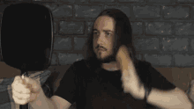 a man with long hair is brushing his hair with a mirror