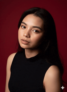 a woman in a black tank top is looking at the camera with a red background