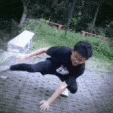 a person wearing a black shirt that says ' samurai ' on it is doing a trick on the ground