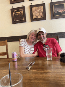 a man and woman sit at a table with a can of purple soda next to them