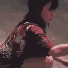 a woman in a red shirt is kneeling on the ground .