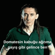a man with long hair is wearing a green shirt with the words domatesin kabuğu agzima