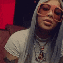 a woman with long white hair wearing sunglasses and a necklace .