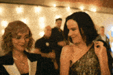 two women are standing next to each other in a room and smiling at each other