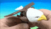 a person is holding a toy eagle with a yellow beak