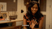 a woman sitting at a desk with her hands folded and the word chuckling above her