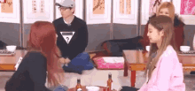 a group of women are sitting around a table with bottles of wine .