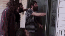 a man with a beard is standing in front of a door