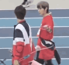 two young men are standing next to each other on a track holding bows and arrows .