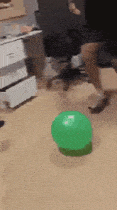 a person is kicking a green exercise ball on the floor