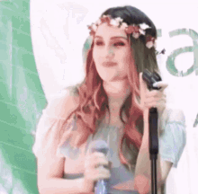 a woman with a flower crown on her head is singing into a microphone