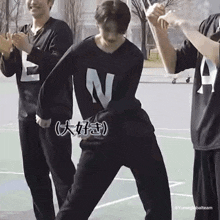 a man in a black shirt with the letter n on it is standing on a basketball court .